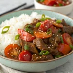 Beef tomato recipe – A flavorful stir-fry with tender beef, juicy tomatoes, and green onions, served with rice and garnished with sesame seeds.