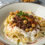 Turkish pasta recipe with creamy garlic yogurt sauce, spiced ground beef, crispy chickpeas, and a buttery chili drizzle, garnished with fresh parsley.